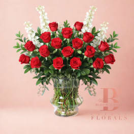 Red roses arranged in a clear glass vase with white accent flowers