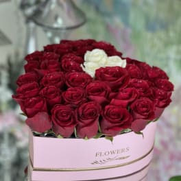 Red and white roses arranged in a pink hat box