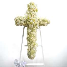 White floral cross on a stand with roses and lilies