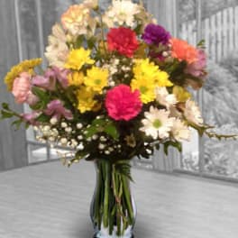 Mixed bouquet of colorful carnations and daisies in a glass vase