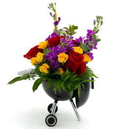 Bouquet of red and yellow roses with purple flowers in a black grill-shaped container