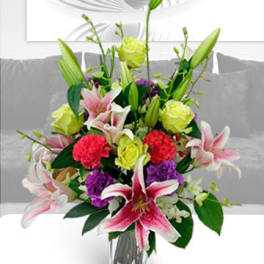 Mixed bouquet of lilies, roses, and carnations in a clear glass vase