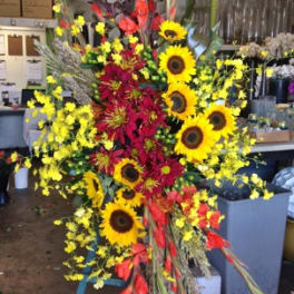 Tall floral arrangement with sunflowers, red blooms, and yellow accents