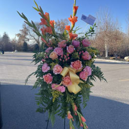 Standing floral spray with pink roses and orange gladiolus on an easel