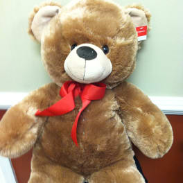 Large brown teddy bear with a red ribbon bow