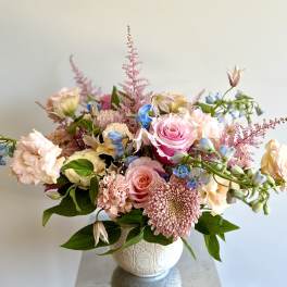 Pink and peach floral arrangement in a white vase