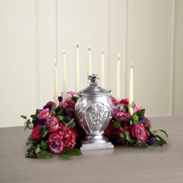 Pink rose arrangement with tall white candles around a silver urn