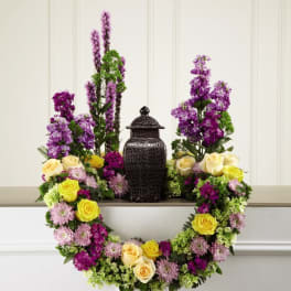 Purple and yellow floral wreath around a black urn