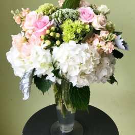 Bouquet of pink and white roses with hydrangeas in a clear glass vase