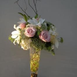 Pink roses and white lilies arranged in a tall glass vase