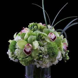 Green and white floral arrangement in a clear glass vase
