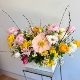 Mixed bouquet in a white rectangular container with pink, yellow, and white blooms