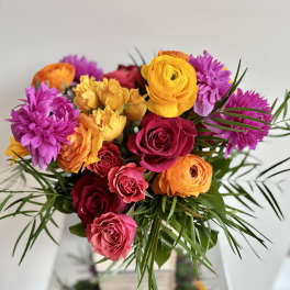 Bright bouquet of roses and purple blooms with palm-like greenery
