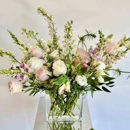 Loose bouquet of pale pink and white flowers in a clear glass vase