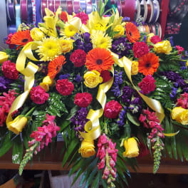 Large colorful floral casket spray with yellow, pink, purple, and orange blooms