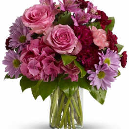 Pink roses and purple daisies in a clear glass vase