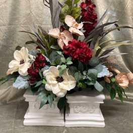 Floral arrangement with cream and burgundy blooms in white pedestal containers