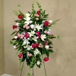 Standing floral spray with white lilies, pink roses, and red blooms on an easel