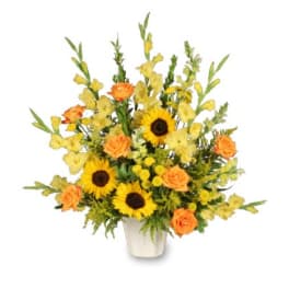 Tall yellow and orange flower arrangement with sunflowers and roses in a white container