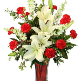 Tall vase arrangement of white lilies and red carnations with white accent flowers