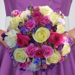 Handheld bouquet of pink, yellow, and purple flowers