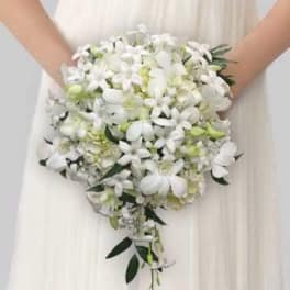 Bride holding a cascading white bouquet with green accents