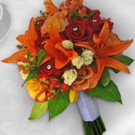 Bouquet of orange lilies and red roses with green leaves