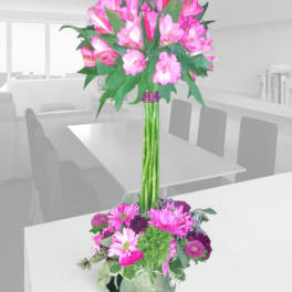 Tall pink floral arrangement in a glass vase with a smaller matching base arrangement