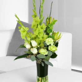 Tall green and white floral arrangement in a clear glass vase