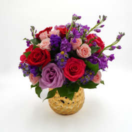 Mixed bouquet of red, pink, and purple roses in a gold vase