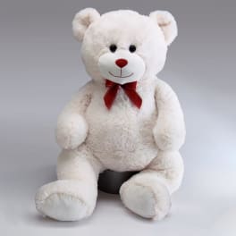 White teddy bear with a red bow sitting on a gray background