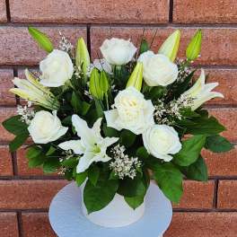 White roses and lilies arranged in a white vase