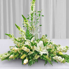 White floral centerpiece with lilies and tall snapdragons on a table