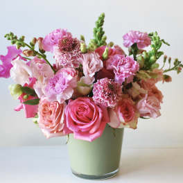 Pink and peach bouquet of roses and carnations in a green vase