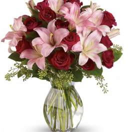 Bouquet of pink lilies and red roses in a clear glass vase