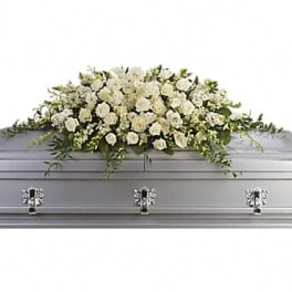 White floral casket spray on a gray casket