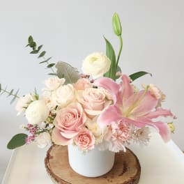 Pink and white floral arrangement in a white vase with a pink lily