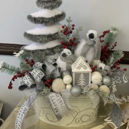 Winter holiday centerpiece with a faux tree, penguins, and silver ribbons