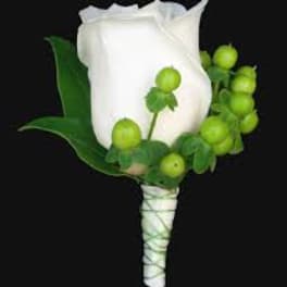 White rose boutonniere with green berries and leaves