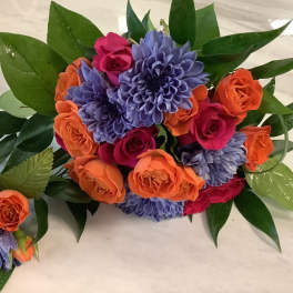 Bouquet of orange and pink roses with purple flowers and glossy leaves