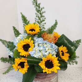 Sunflowers and blue hydrangeas in a rustic container