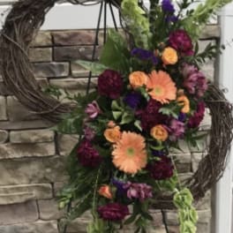 Floral standing spray with orange and purple flowers on a wreath stand