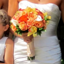 Bride holding a bouquet of orange and yellow roses with white calla lilies