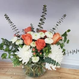 Orange roses and white chrysanthemums in a glass vase with eucalyptus