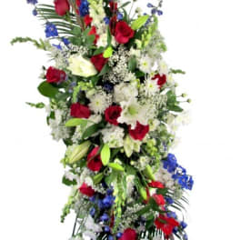 Tall standing floral spray with red roses, white lilies, and blue accents