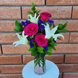 Pink roses and white lilies in a clear glass vase