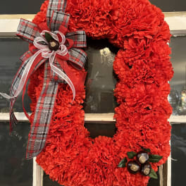 Red carnation wreath with plaid ribbon bow on a window