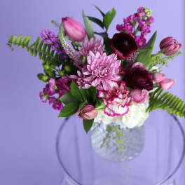 Pink and burgundy flowers arranged in a clear glass vase