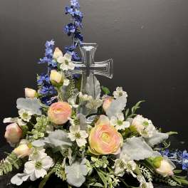 Floral arrangement with a clear cross centerpiece and pastel blooms