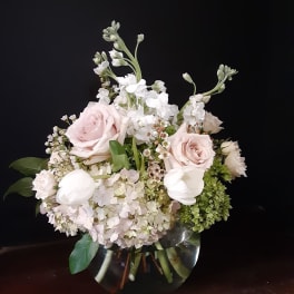 Soft pink roses and white flowers arranged in a clear glass vase